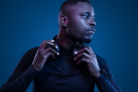 Athletic black man adjusting headphones and looking awayの写真素材