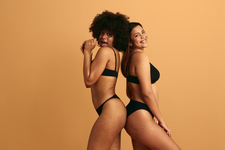 Joyful young diverse female friends smiling at camera in studioの写真素材