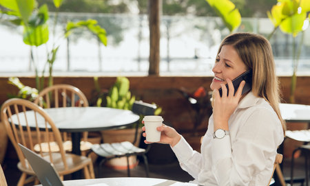 Cheerful executive talking on smartphone at cafeの写真素材