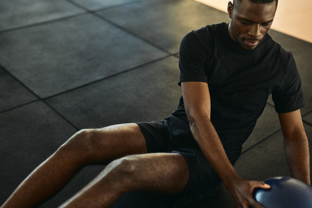 Black sportsman doing exercise with medicine ballの写真素材