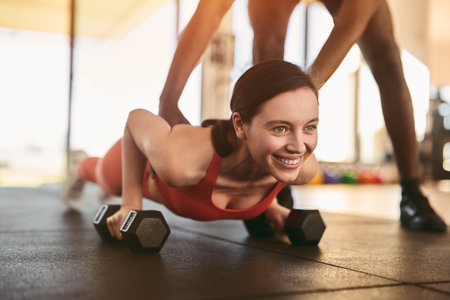 Black trainer helping woman with plank exercise