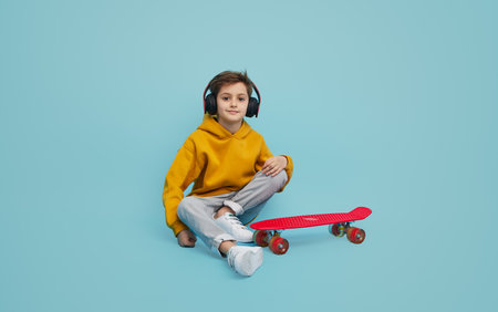 Stylish youngster listening to music near longboardの写真素材