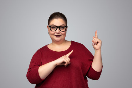Content plus size woman pointing up in studioの写真素材