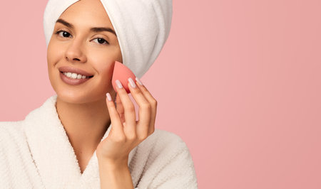 Happy woman using makeup sponge in studioの写真素材