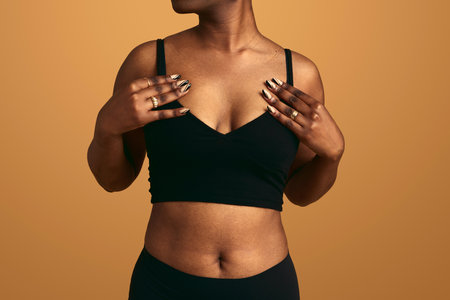 Crop plump black woman adjusting bra in studioの写真素材