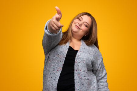 Smiling young overweight woman showing finger gun gesture in studioの写真素材