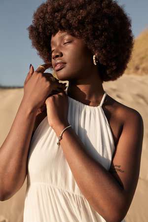 Sensual black woman in white dress in countryside