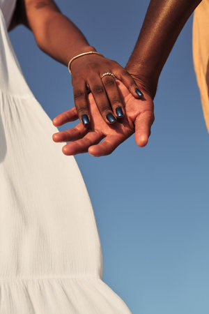 Crop African couple holding hands in sunlight