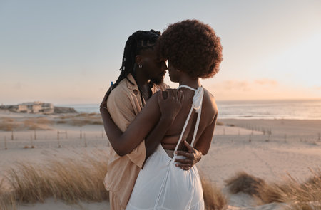 African couple hugging on beach at sunsetの写真素材