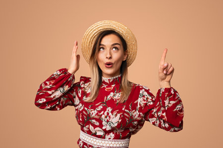 Stylish woman in straw hat pointing up in studioの写真素材