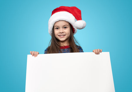 Smiling girl in santa hat showing blankの写真素材