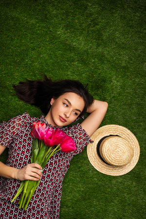 Young woman with flowers lying on grassの写真素材