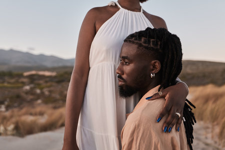 Black woman embracing boyfriend kneeling on beachの写真素材