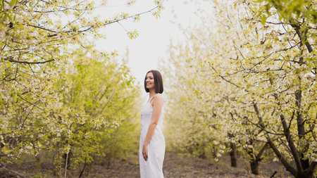 Woman Enjoying a Stroll Through Blossoming Orchard in Spring