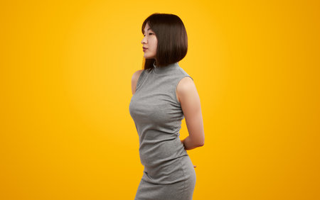 Elegant Woman Posing in Grey Dress Against Yellow Background