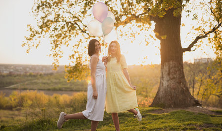 Joyful Women Holding Balloons in a Sunlit Parkの写真素材