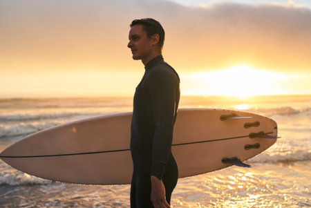 Surfer Carrying Board at Sunset on the Beachの写真素材