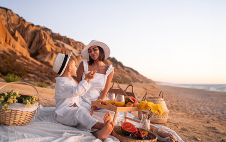 Mother And Son Enjoying A Beach Picnic At Sunsetの写真素材