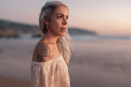 Woman With Tattoo Posing On Beach During Sunset Near Ocean Wavesの写真素材
