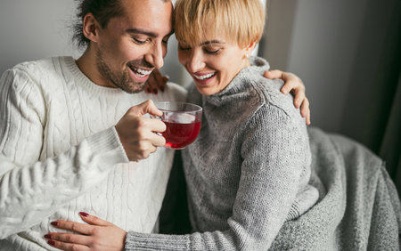 Happy Couple Enjoying Warm Tea Together At Homeの写真素材