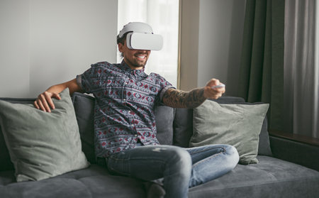 Man Playing VR Game on Couch with Controllerの写真素材