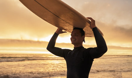 Surfer Carrying Surfboard at Sunset Beach