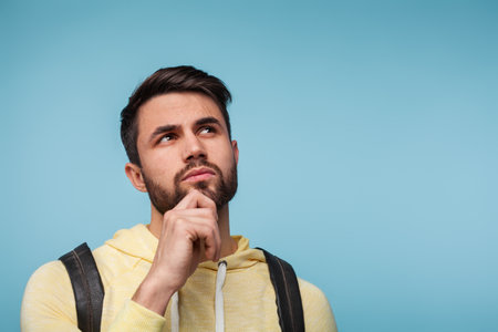 Pensive Man Contemplating Decision Against a Solid Bright Backdropの写真素材