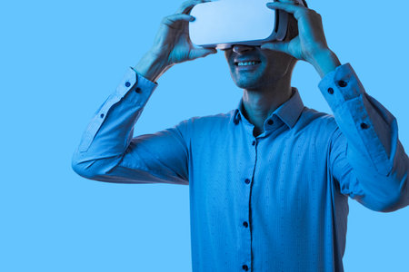 Businessman Experiencing Virtual Reality With VR Goggles Against Blue Backgroundの写真素材