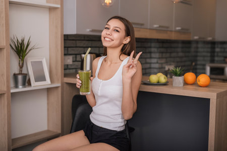 Smiling Woman Enjoying a Healthy Smoothie in a Modern Kitchenの写真素材