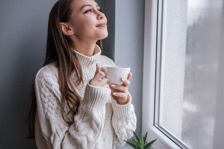 Young Woman Relaxing With A Warm Beverage Near A Windowの写真素材