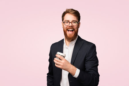Smiling Businessman With Coffee Cup Against Pink Background Demonstrates Joyful Personalityの写真素材
