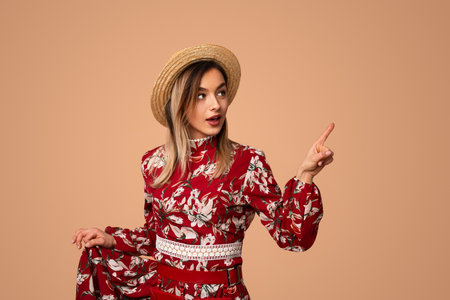 Content stylish lady pointing away in beige studioの写真素材