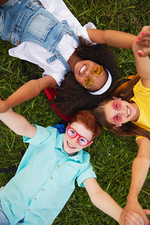 Group of Happy Kids Lying on Grass in Sunny Park, Smiling, and Having Funの写真素材