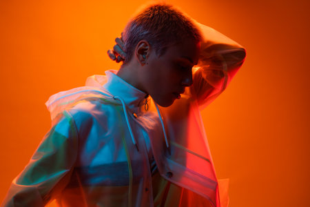 Creative Portrait Of Woman In Vibrant Lighting Against Orange Backgroundの写真素材