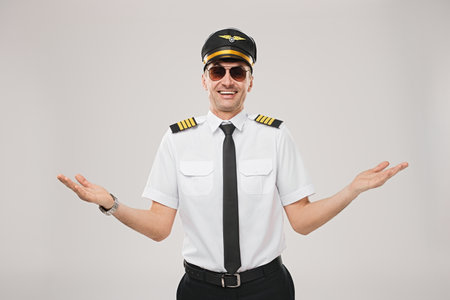 Confident Male Airline Pilot in Uniform Shrugging With a Friendly Smileの写真素材