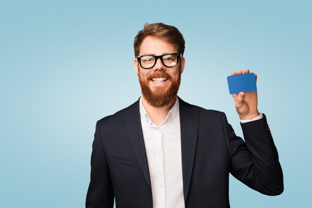 Smiling Businessman Holding a Blank Blue Card Against a Minimalist Backgroundの写真素材