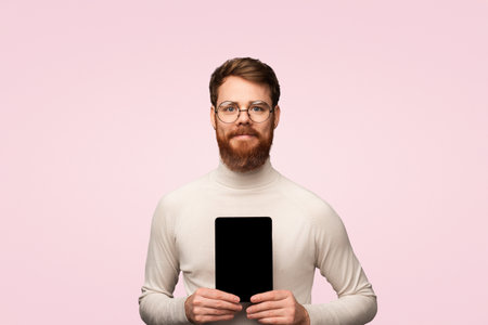 Smiling Man Holding Tablet Device Against Minimalist Backgroundの写真素材