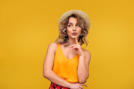 Fashionable Woman in Hat Posing Against Bright Yellow Backgroundの写真素材