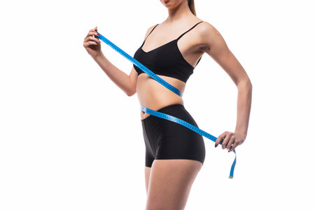 Woman Measuring Waist With Blue Tape for Fitness and Health Goalsの写真素材
