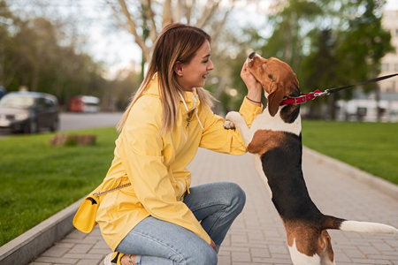 Woman in Yellow Jacket Bonding With Happy Dog During a Walk in the Parkの写真素材