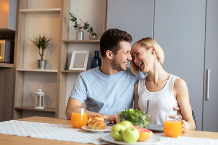 Happy Couple Enjoying Breakfast Together in a Modern Home Kitchenの写真素材