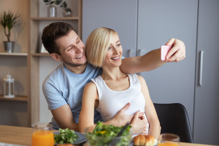 Couple Smiling While Taking a Selfie Together in a Cozy Home Settingの写真素材