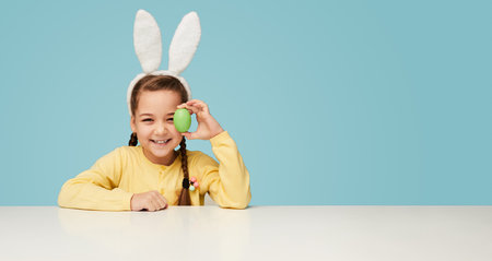 Playful girl in bunny ears posing with Easter eggの写真素材