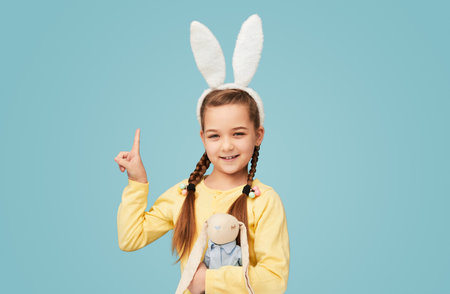 Cute girl in bunny ears pointing upの写真素材
