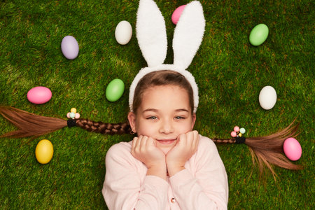 Cute girl lying on grass with Easter eggsの写真素材