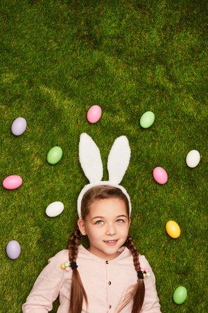 Cute dreamy girl in bunny ears on green meadowの写真素材