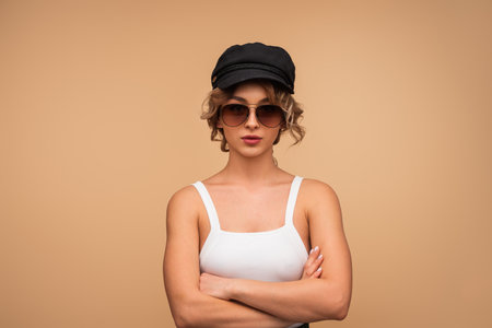 Stylish Woman Posing in Sunglasses and Hat Against Neutral Backgroundの写真素材