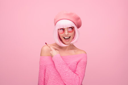 Cheerful Woman in Pink Outfit and Sunglasses on Matching Backgroundの写真素材
