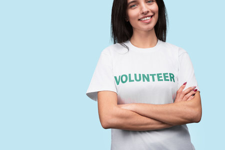 Confident Volunteer Woman Smiling in a White Shirt on Blue Backgroundの写真素材