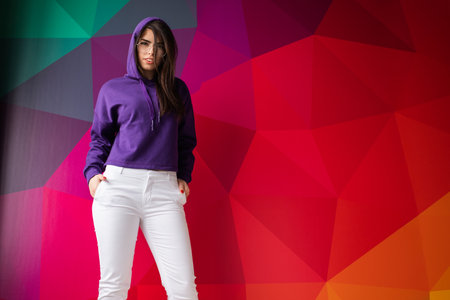 Stylish Woman in Purple Hoodie Posing Against Colorful Geometric Backgroundの写真素材